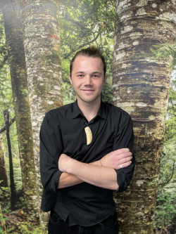 A man standing in front of a green forest. 