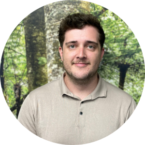 Josh has short dark hair and stubble. He is wearing a beige polo shirt