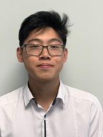 Eden has short spiky dark hair and glasses. He is wearing a white shirt