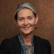 Professor Sunny Collings is wearing a black blaser over a patterned blouse and scarf. Her hair is tied back from her face
