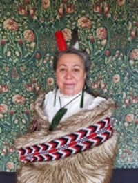 Marama Parore, wearing a korowai, stands facing the camera smiling.