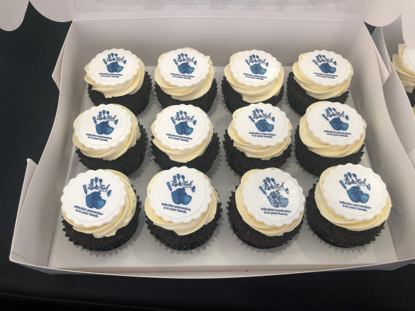 A box of 12 cupcakes with a handprint and slogan on the icing