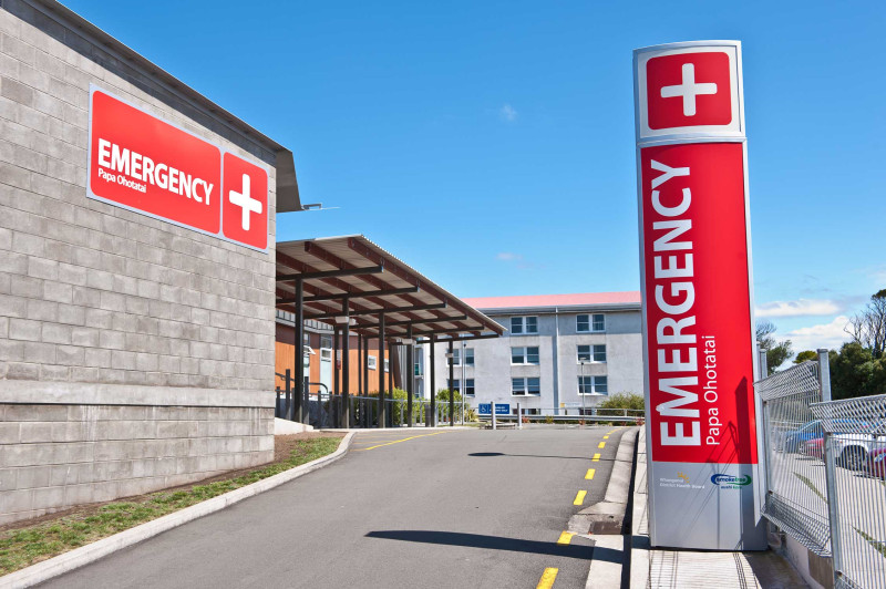 Two bright red signs point to the emergency department of a hospital. 