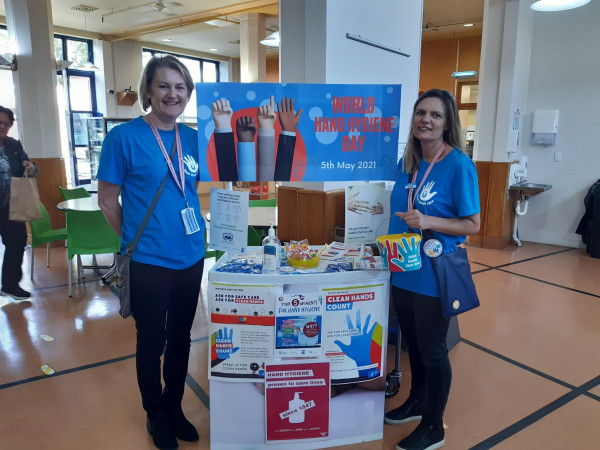 Two members of the Hutt Valley DHB IPC team in front of their foyer banner on WHHD 2021