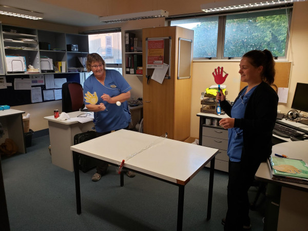 Two IPC nurse specialists play table tennis bats in the shape of hands