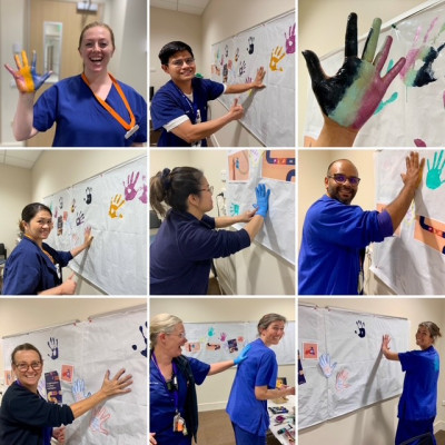 A collage of people in scrubs making handprints with paint on a large white piece of paper.